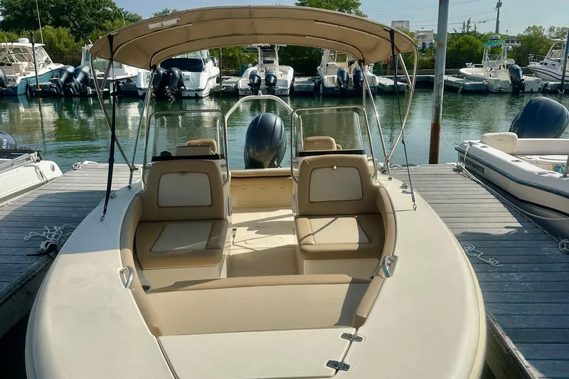 Slide: The Image of 2023 Scout 195 Sport Dorado boat docked at marina, featuring beige seating and canopy. - 2