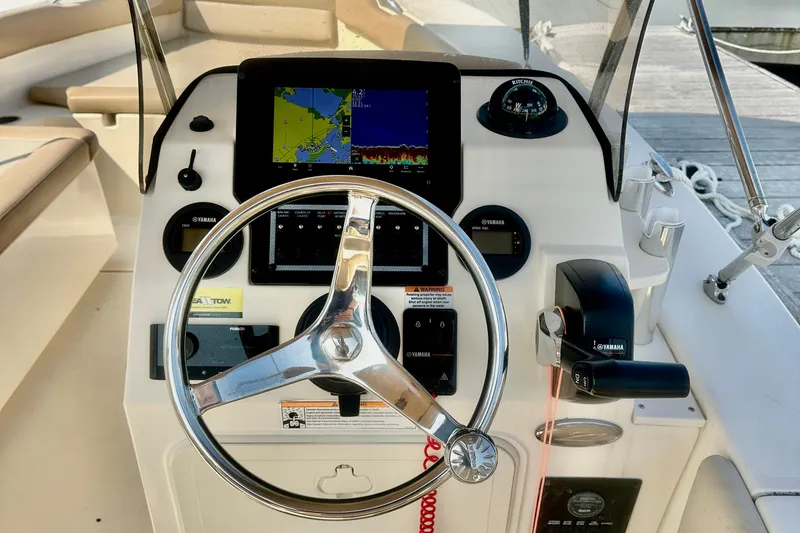 Slide: The Image of 2023 Scout 195 Sport Dorado boat dashboard with steering wheel and navigation display. - 3