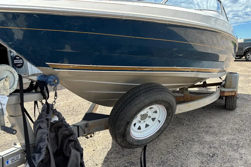 Slide: The Image of 1995 Bayliner Maxum boat on trailer, blue hull, parked on gravel. - 4