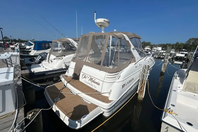 The Image of 2001 Larson Cabrio 330 boat docked at marina, featuring tan canopy and sleek design. - 0