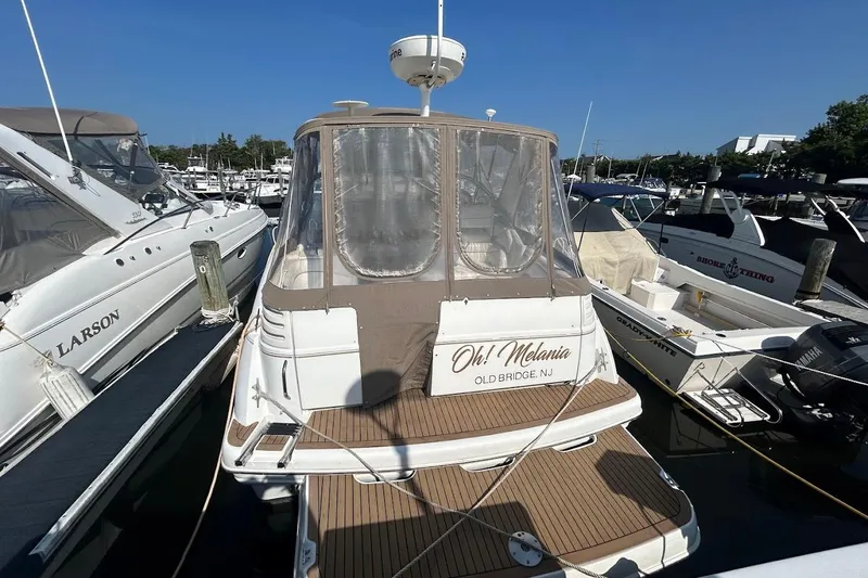 Slide: The Image of 2001 Larson Cabrio 330 boat docked at marina, featuring tan canopy and wooden deck. - 2