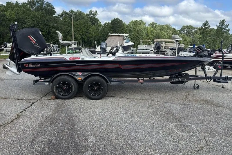 Slide: The Image of 2020 Bass Cat Cougar FTD boat on trailer, parked outdoors with trees in background. - 11