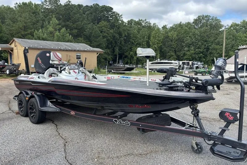 Slide: The Image of 2020 Bass Cat Cougar FTD boat on trailer, parked outdoors with trees in background. - 6