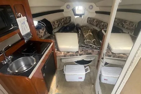 Slide: The Image of 2003 Rinker Fiesta Vee 270 cabin interior with kitchenette, seating, and storage coolers. - 3