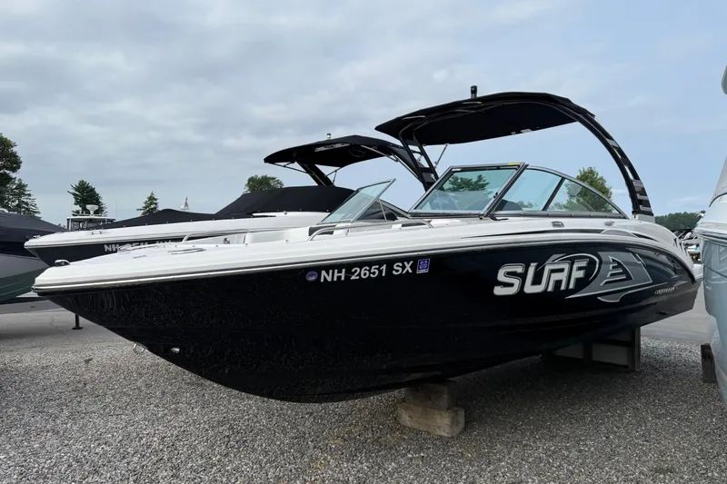 Slide: The Image of 2024 Chaparral 23 Surf boat displayed outdoors on gravel. - 1