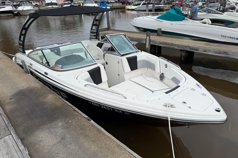 Slide: The Image of 2024 Chaparral 23 Surf boat docked at marina, featuring sleek design and spacious seating. - 2