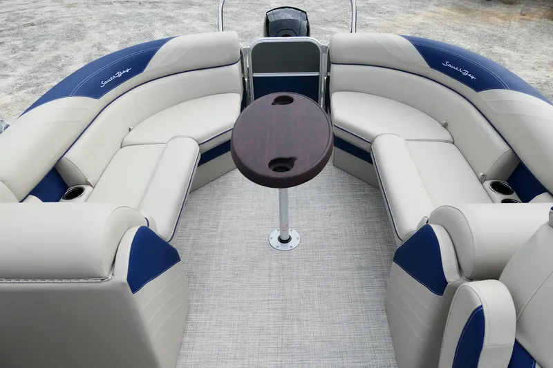 Slide: The Image of 2022 South Bay 224 RS pontoon boat interior with plush seating and central table. - 3