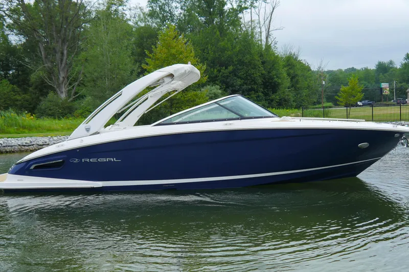 Slide: The Image of 2018 Regal 2800 Bowrider boat on calm water, surrounded by lush greenery. - 3