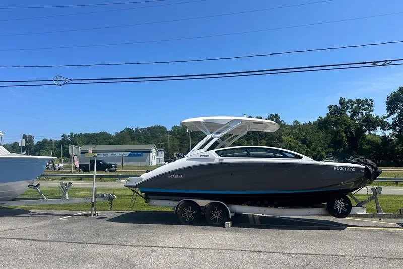 Slide: The Image of 2022 Yamaha Boats 275SD on trailer, parked outdoors under clear blue sky. - 0