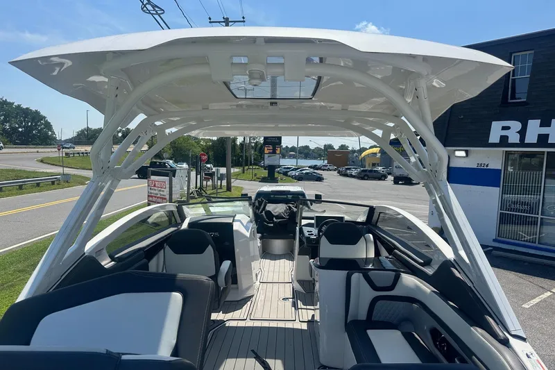 Slide: The Image of 2022 Yamaha Boats 275SD interior with seating and helm, parked near a road. - 29