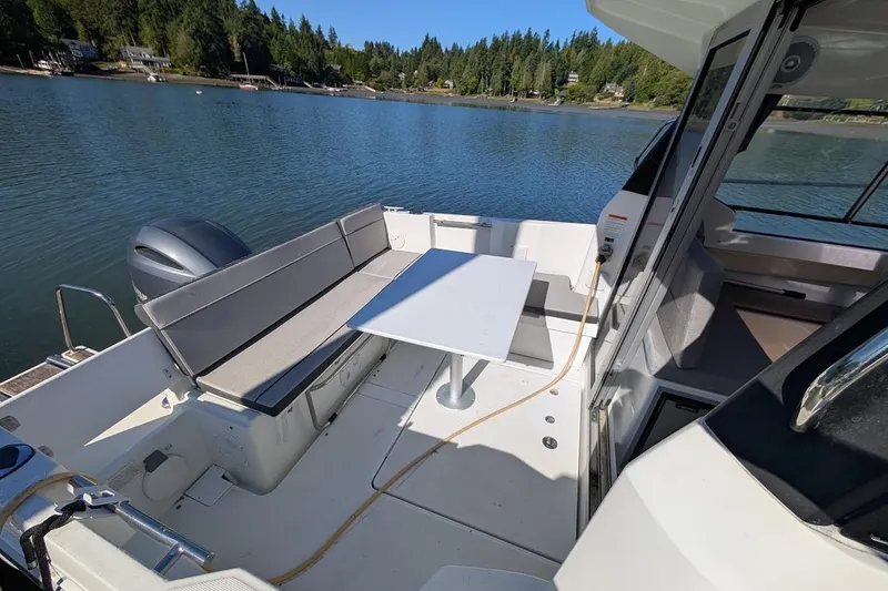 Slide: The Image of 2020 Jeanneau NC 695 Series 2 boat interior with seating and table, docked on a serene lake. - 21