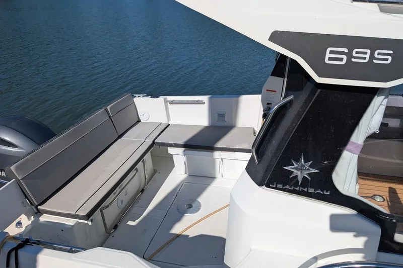 Slide: The Image of 2020 Jeanneau NC 695 Series 2 boat interior with seating, docked on calm water. - 22