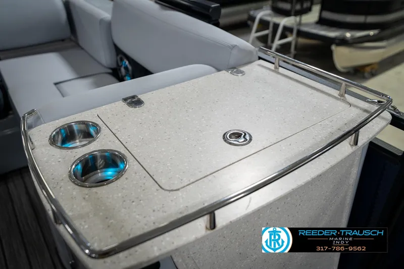 Slide: The Image of 2020 Harris Solstice boat interior with seating and table, displayed in a showroom. - 27