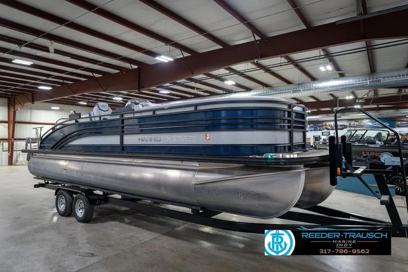 Slide: The Image of 2020 Harris Solstice pontoon boat in showroom, front view with blue and white design. - 4