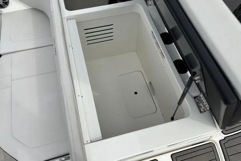 Slide: The Image of 2023 Sea Ray SPX 210 Outboard storage compartment with white interior and cushioned seating. - 15