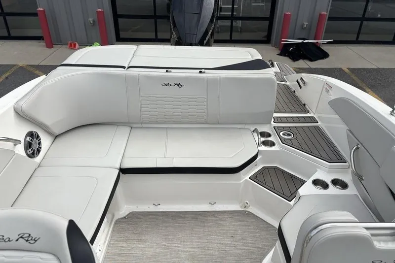 Slide: The Image of 2023 Sea Ray SPX 210 Outboard boat interior with white seating and wood accents. - 16