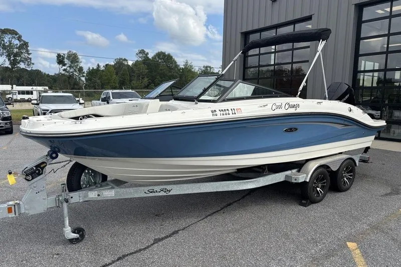 Slide: The Image of 2023 Sea Ray SPX 210 Outboard boat on trailer, blue and white, parked outdoors. - 4