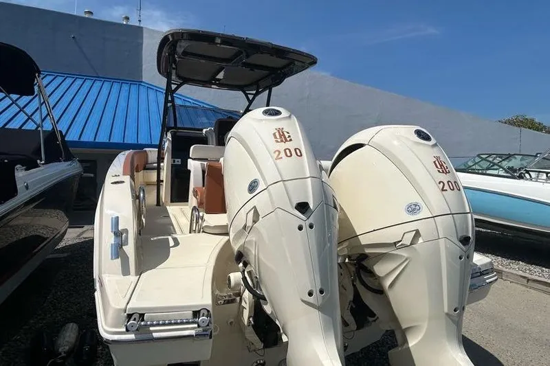 Slide: The Image of 2024 Capoforte FX270 boat with dual 200 horsepower engines, docked under clear blue sky. - 2