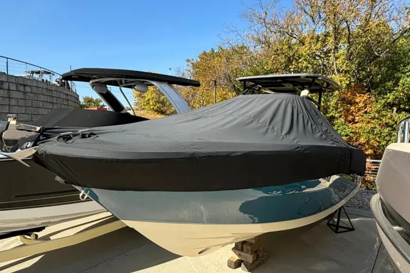 Slide: The Image of 2024 Capoforte FX270 boat covered, parked outdoors with trees in the background. - 23