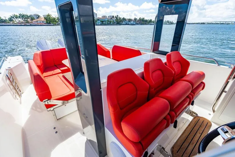 Slide: The Image of 2023 Nimbus Tender 11 boat interior with vibrant red seating and scenic water view. - 10