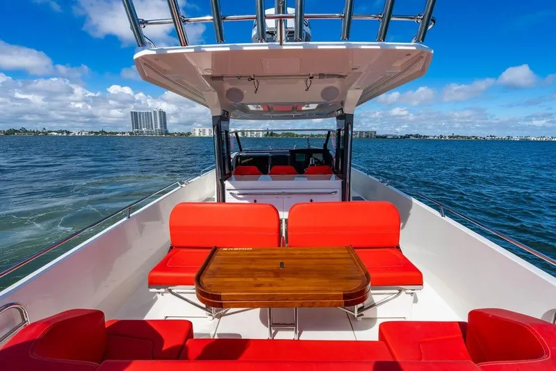 Slide: The Image of 2023 Nimbus Tender 11 boat with red seating, wooden table, and ocean view. - 12