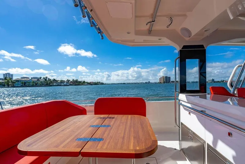 Slide: The Image of Luxurious 2023 Nimbus Tender 11 yacht interior with red seating and wooden table, ocean view. - 13