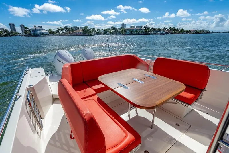 Slide: The Image of 2023 Nimbus Tender 11 boat with red seating and wooden table on a sunny day. - 14