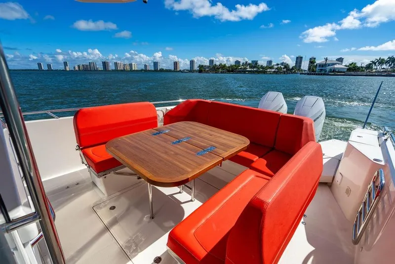 Slide: The Image of Luxury Nimbus Tender 11 boat with red seating, wooden table, and scenic waterfront view. - 16