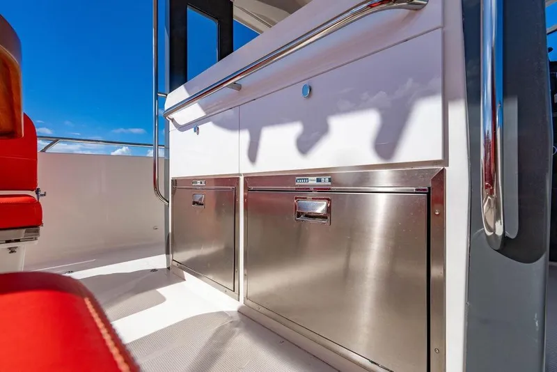 Slide: The Image of 2023 Nimbus Tender 11 interior with stainless steel storage and red seating under blue sky. - 20