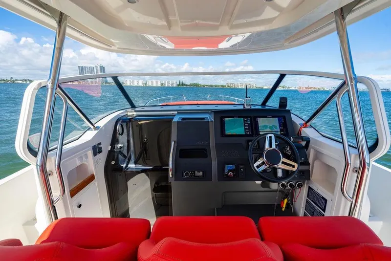 Slide: The Image of 2023 Nimbus Tender 11 boat cockpit with red seats and modern navigation system. - 4