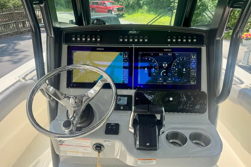 Slide: The Image of 2024 Boston Whaler 250 Outrage dashboard with dual Simrad displays and steering wheel. - 10