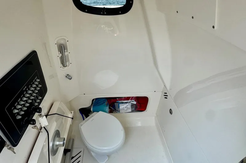 Slide: The Image of 2024 Boston Whaler 250 Outrage interior cabin with toilet and control panel. - 14