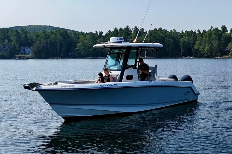 Slide: The Image of 2024 Boston Whaler 250 Outrage boat on a serene lake with forested background. - 4