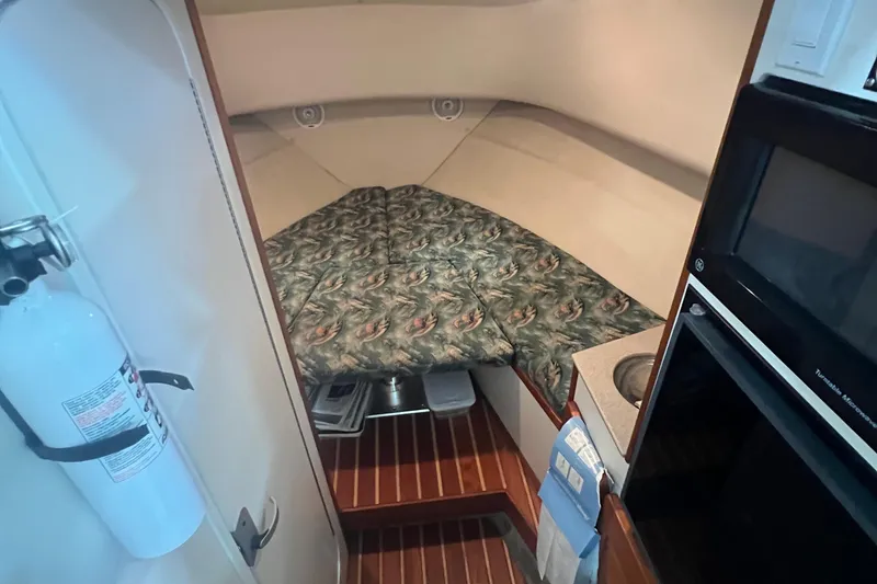 Slide: The Image of 2001 Pursuit 3070 Offshore cabin interior with bed, kitchenette, and fire extinguisher. - 19