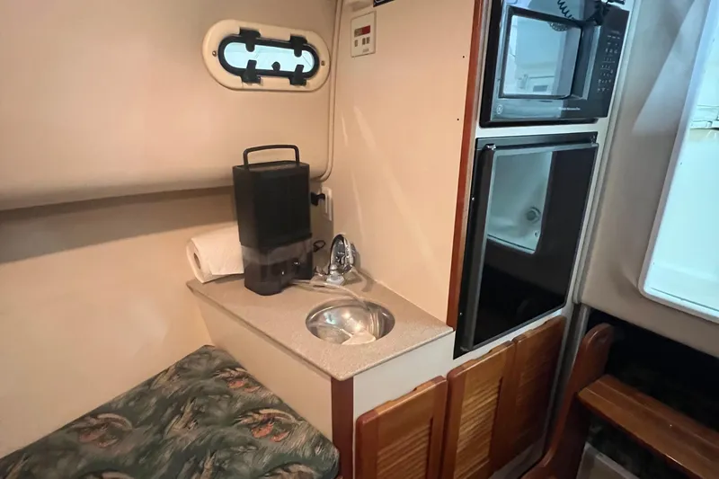 Slide: The Image of 2001 Pursuit 3070 Offshore cabin interior with sink, microwave, and seating area. - 20