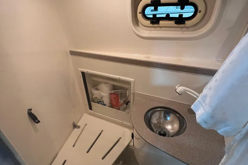 Slide: The Image of 2001 Pursuit 3070 Offshore boat bathroom with sink, storage, and porthole window. - 23