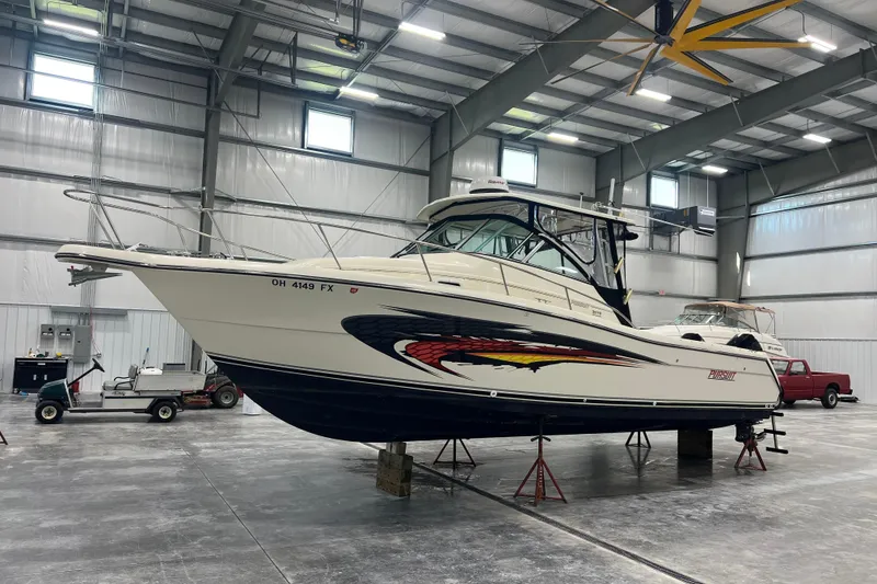 Slide: The Image of 2001 Pursuit 3070 Offshore boat in a spacious indoor storage facility. - 3