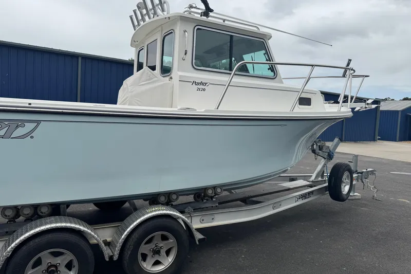 Slide: The Image of 2014 Parker 2120 Sport Cabin boat on trailer, parked near blue building. - 1