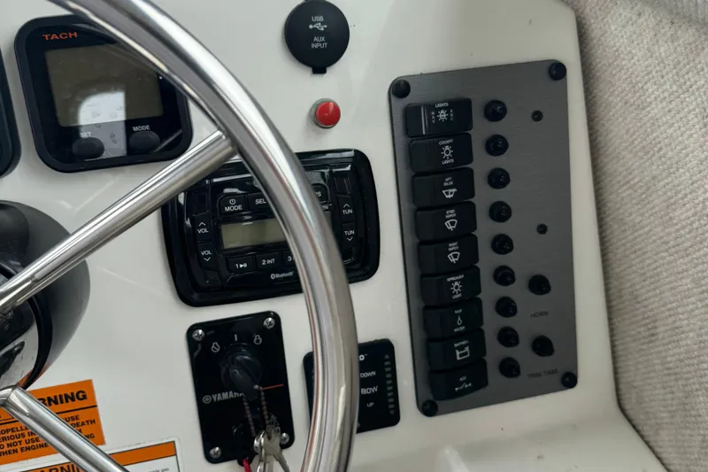 Slide: The Image of Control panel of a 2014 Parker 2120 Sport Cabin boat with steering wheel and switches. - 13