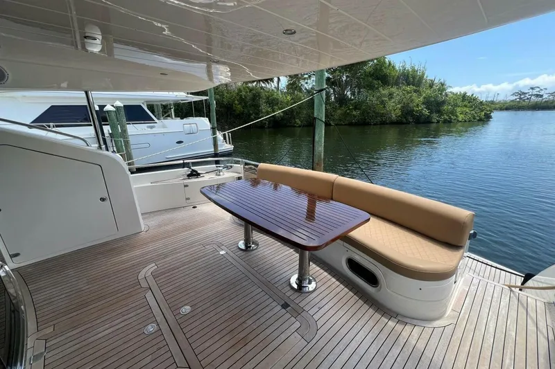 Slide: The Image of 2006 Princess 67 Flybridge yacht with elegant deck seating and table, docked by serene water. - 5