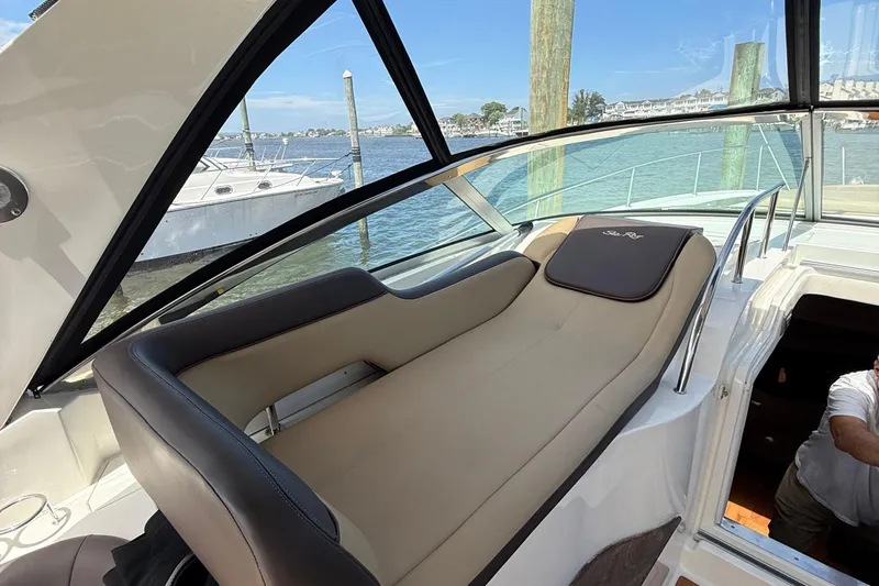 Slide: The Image of 2015 Sea Ray 350 Sundancer interior with beige seating, docked by the water. - 13