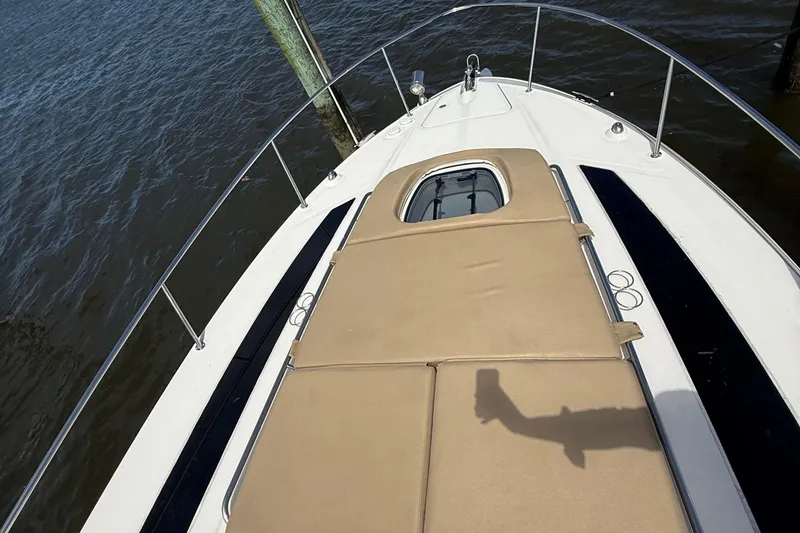 Slide: The Image of 2015 Sea Ray 350 Sundancer boat deck with tan cushions, docked by water. - 19