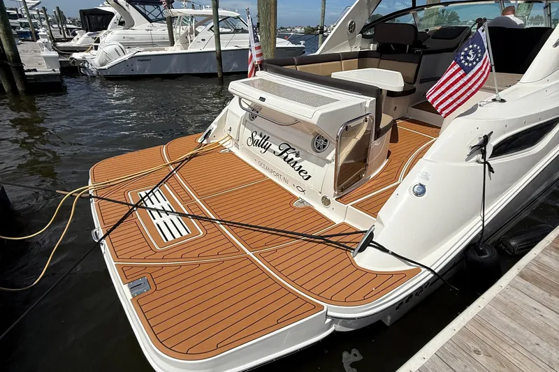 Slide: The Image of 2015 Sea Ray 350 Sundancer docked, featuring teak deck and American flags. - 2