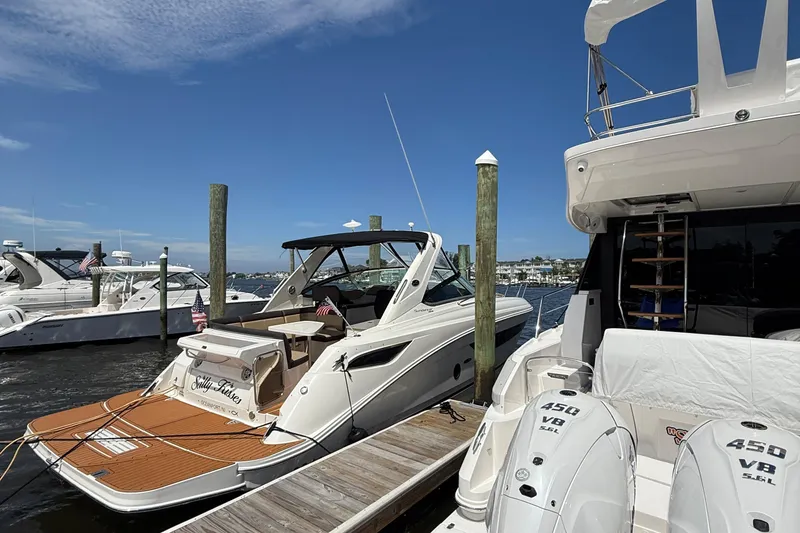 Slide: The Image of 2015 Sea Ray 350 Sundancer docked at marina, clear blue sky, adjacent boats visible. - 4