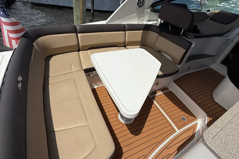 Slide: The Image of 2015 Sea Ray 350 Sundancer boat interior with cushioned seating and table. - 8