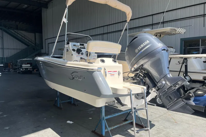 Slide: The Image of 2026 Scout 188 Sportfish boat displayed in a showroom with banners and equipment. - 1