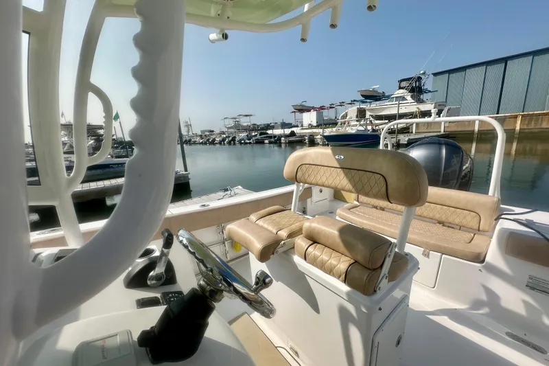 Slide: The Image of 2020 Sportsman Heritage 251 Center Console boat interior at marina, featuring beige seating. - 12