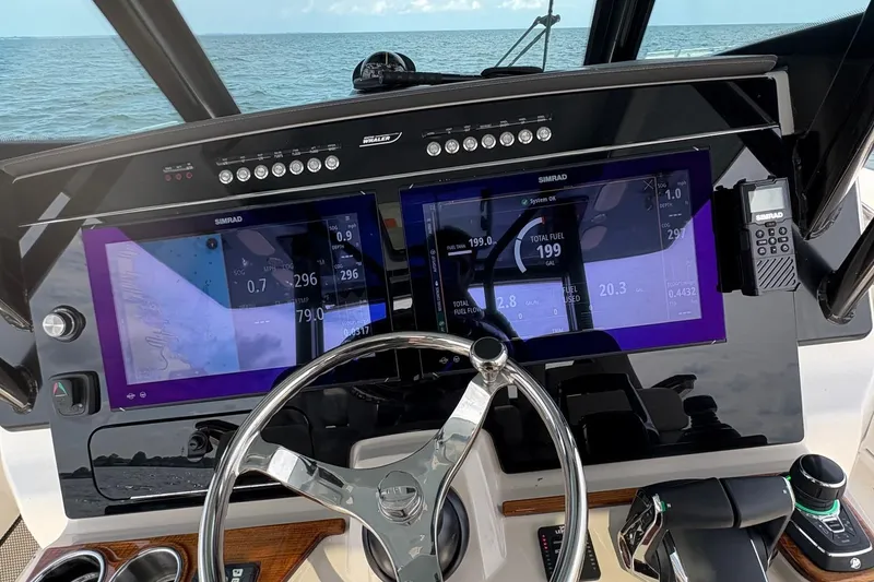 Slide: The Image of Helm of 2025 Boston Whaler 360 Outrage with dual Simrad displays and steering wheel. - 12