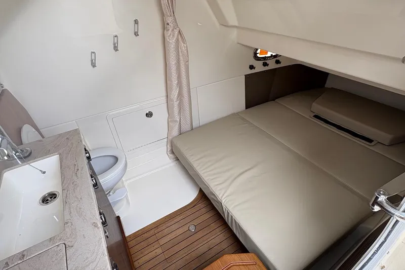 Slide: The Image of 2025 Boston Whaler 360 Outrage cabin interior with bed, sink, and toilet. - 13