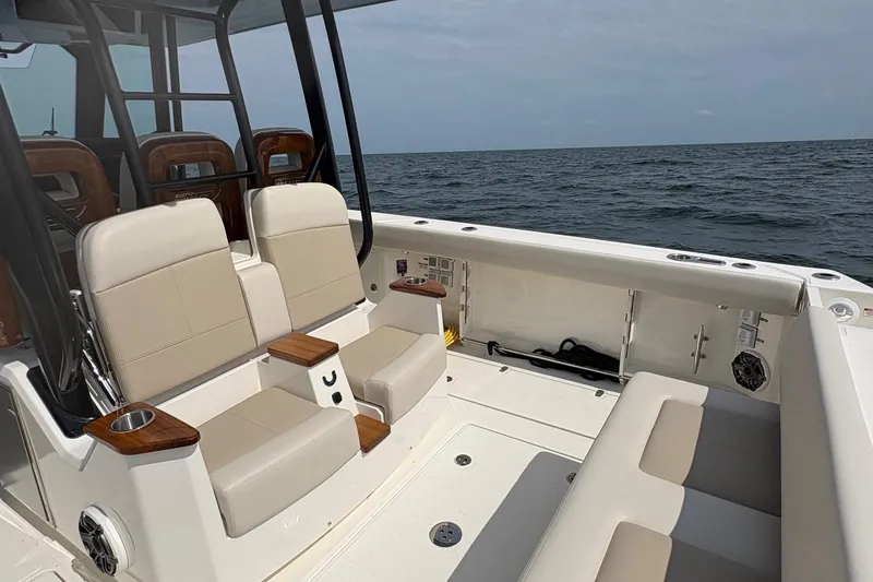 Slide: The Image of 2025 Boston Whaler 360 Outrage boat interior with beige seating and ocean view. - 8